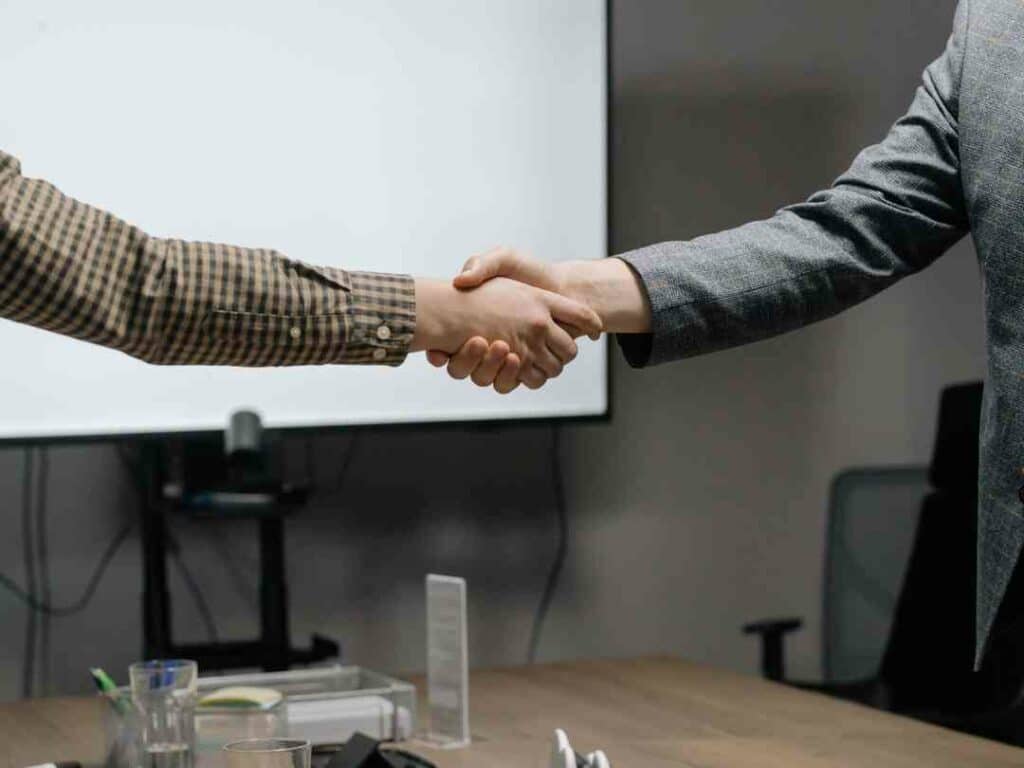 Two people shaking hands over a desk