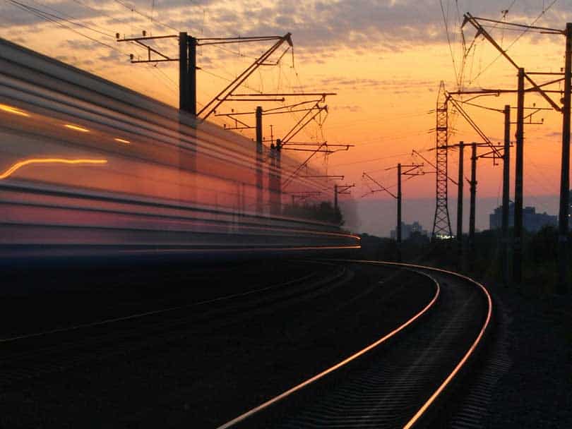 Blurry train travelling on Irish rail network at dusk with electric lines in the background