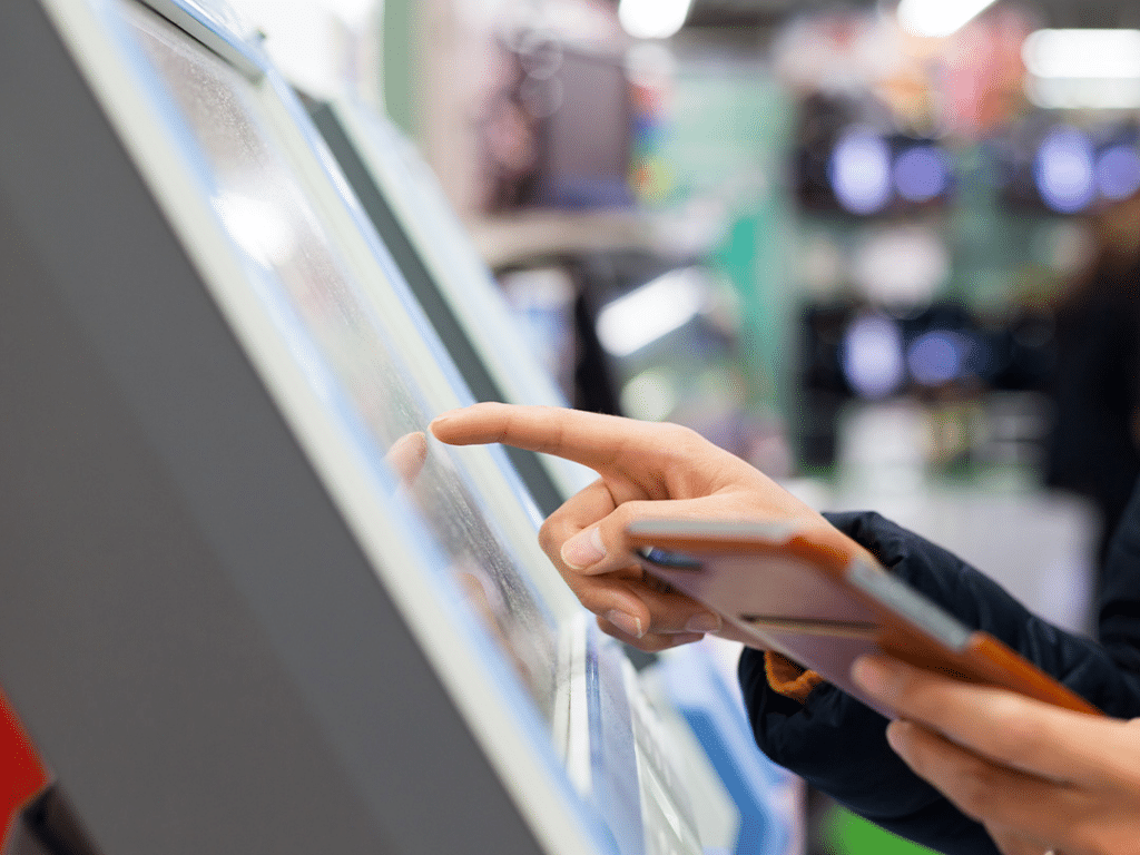 Close up of customer using ticket machine and mobile phone to pay